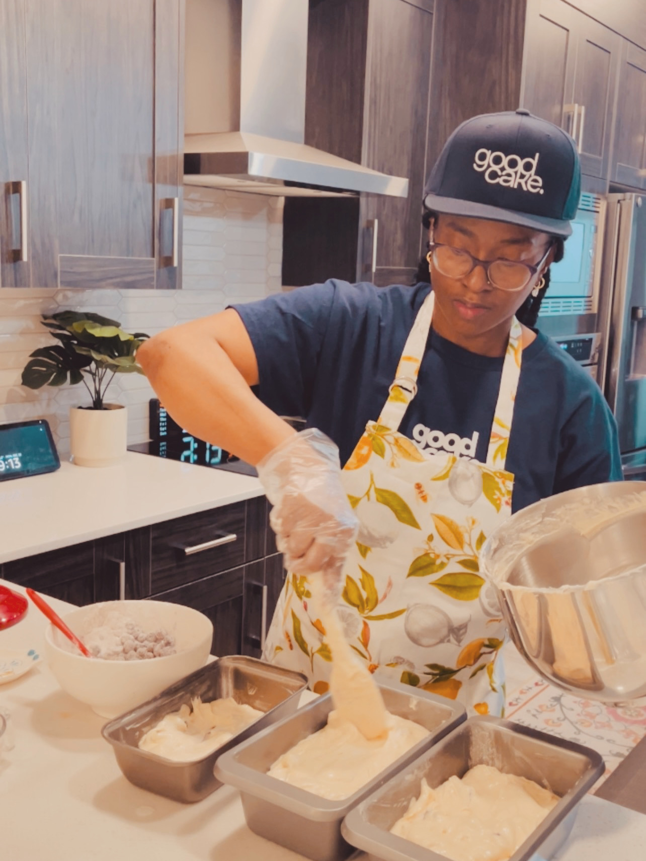 GoodCake baker in a navy hat and citrus apron preparing loaf cakes